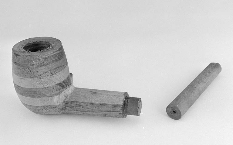 Détail d'un tuyau de bois et d'un second, inséré dans la tige d'une pipe en contreplaqué.
