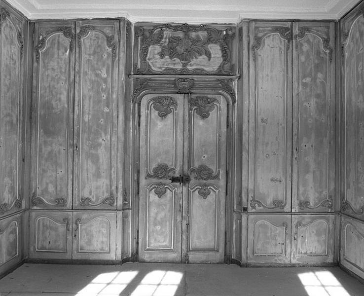 Logis sur cour, intérieur : vue d'ensemble des lambris de la bibliothèque avec la porte d'entrée.