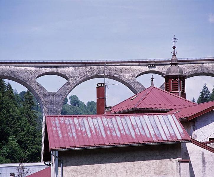 Toitures et clocher avec le grand viaduc en arrière-plan.