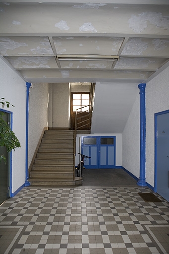 Intérieur de l'entrée : escalier, poteaux en fonte et voûtains.