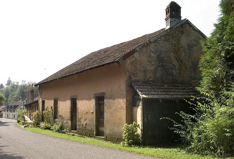 Alignement de façades de logements sur la route de Plombières. Au premier plan : salle de spectacle.