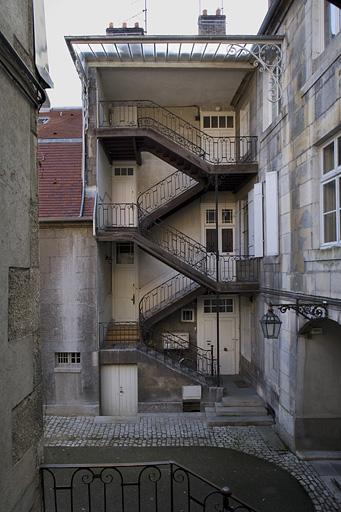 Vue d'ensemble de l'escalier à cage ouverte à gauche de la cour.