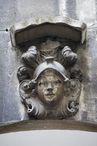 Première cour : détail de la clé d'un arc représentant une tête casquée.