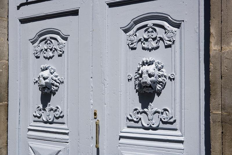 Logis principal : détail des deux vantaux du portail d'entrée décorés d'une tête de lion.