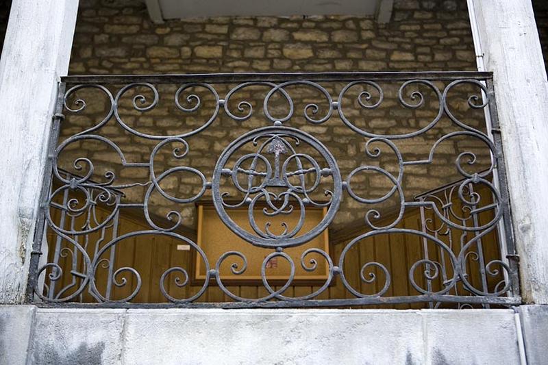 Détail du monogramme situé sur la rampe en ferronnerie de l'escalier à cage ouverte droit.