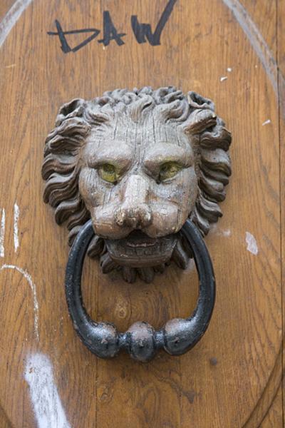 Vantail droit du portail d'entrée : détail du mufle de lion situé sur le panneau central, de face.