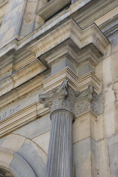 Façade principale : détail du chapiteau d'une colonne encadrant le portail d'entrée, vue éloignée.