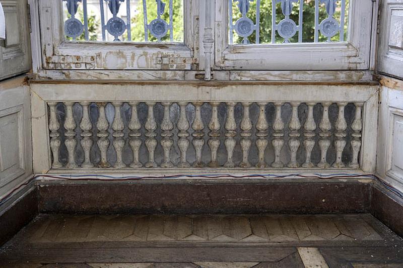 Hôtel en fond de cour, grand salon : décor de balustres sur fond de glace sous une fenêtre.