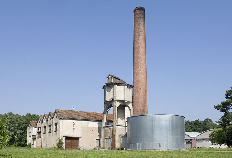 Chaufferie, réservoirs industriels et cheminée vus de trois quarts droite.