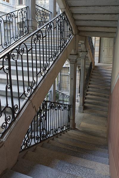 Escalier à cage ouverte : détail de la rampe en fer forgé depuis l'intérieur de l'escalier.