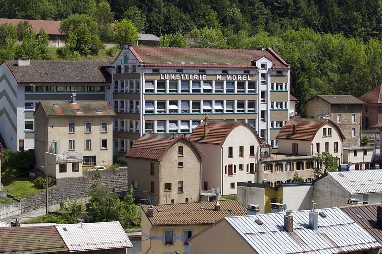 Usine d'horlogerie Odo puis de lunetterie des Ets Marius Morel, Morez (18-22 avenue Charles de Gaulle). Au premier-plan les bâtiments (au toit en carène) de l'usine Pelletier et Cok puis Cok et Cie (8-12 rue de la Paix).