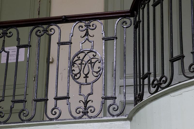 Intérieur, escalier d'honneur : détail du monogramme sur la rampe en fer forgé.