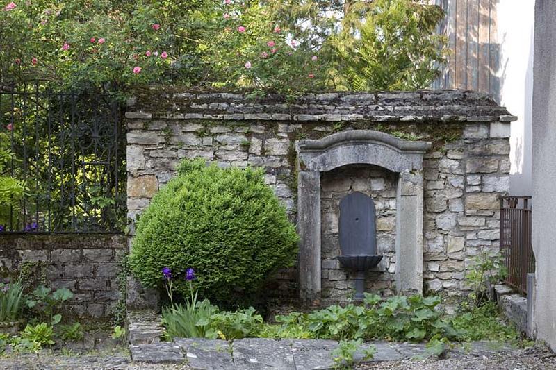 Vue de la borne-fontaine située contre le mur du jardin.