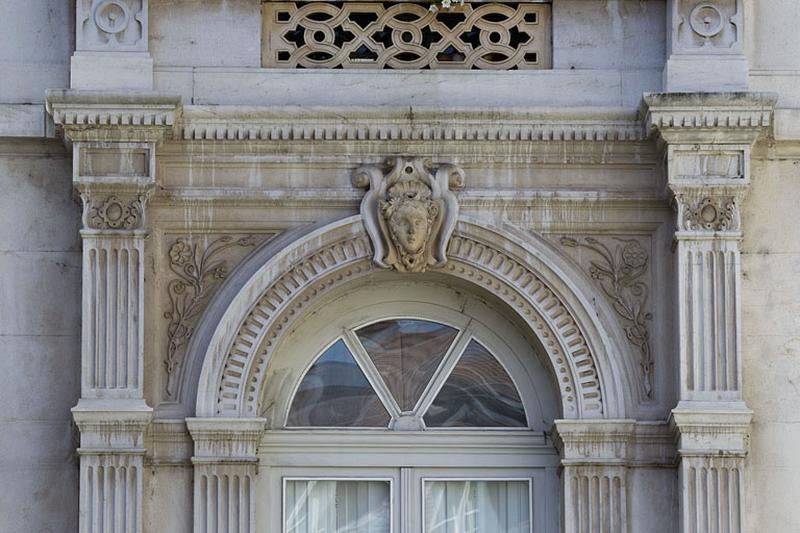 Façade d'angle, rez-de-chaussée : détail du décor, partie supérieure d'une baie.