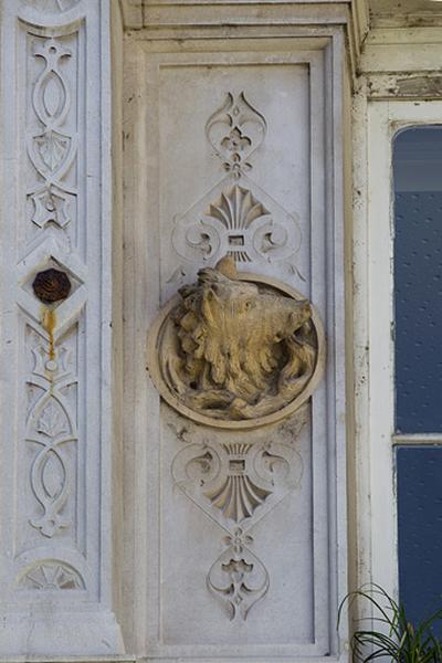 Façade d'angle, deuxième étage, baie centrale, détail du décor gauche : tête de sanglier.