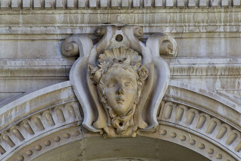 Façade d'angle, rez-de-chaussée, baie centrale, détail du décor de la clé de l'arc : tête de femme.