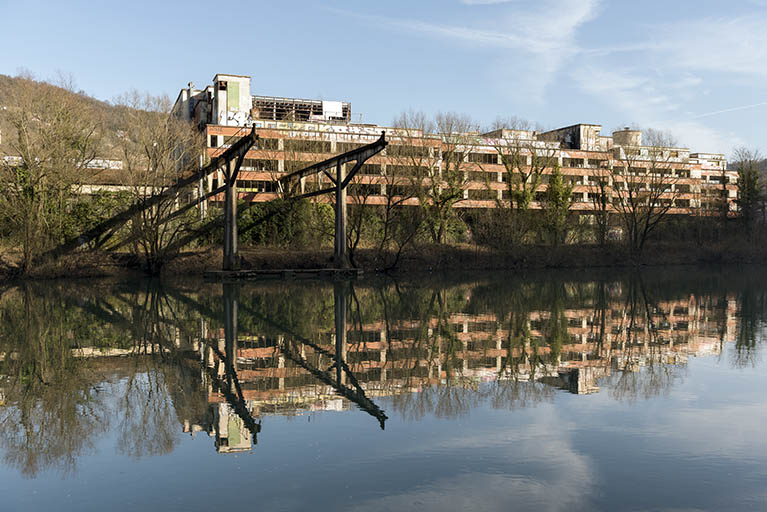 Etat en 2016. Usine A : façade sud des ateliers d'étirage et filature tergal et nylon, et portique du pont roulant, depuis la rive gauche du Doubs.