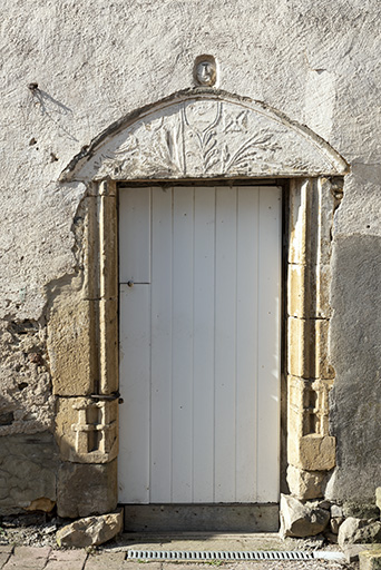 Ferme à l'ouest de l'ancienne cure (parcelles cadastrées D 562 et 446) : tympan en plein cintre décoré d’oiseaux et de feuillages en relief écrasé remployé comme linteau d'une porte aux piédroits moulurés. 
