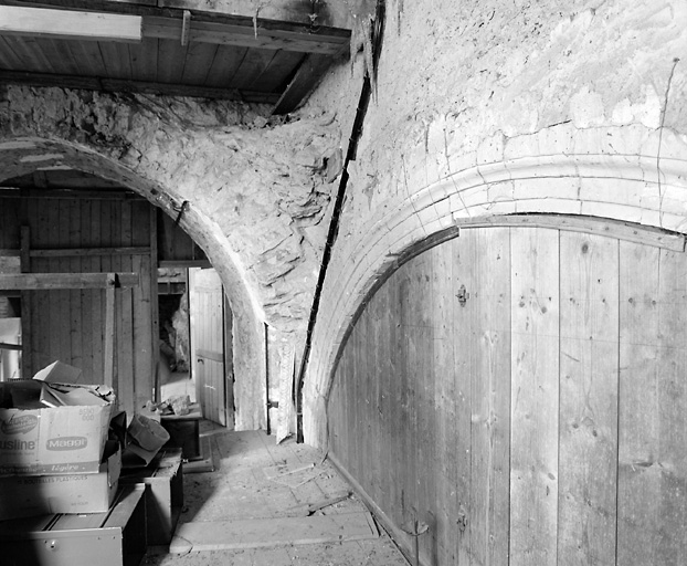 Angle nord-ouest de la chapelle sud, actuellement à l'étage-carré de la sacristie : arcade d'une ancienne absidiole sur le mur ouest et arcade murée sur le mur nord (à droite).