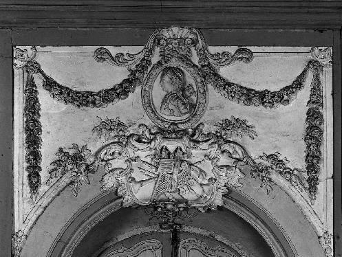 Logis, le grand-salon, décor stuqué au-dessus de la porte d'entrée : trophée et guirlandes.