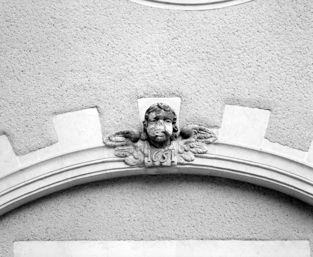 Mascaron et date portée sur l'aile orientale du cloître.