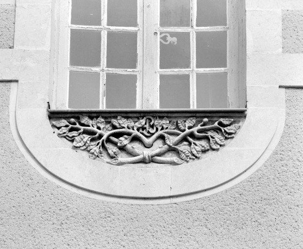 Relief avec le monogramme des hospitalières sur une allège de fenêtre, sur l'aile orientale du cloître.