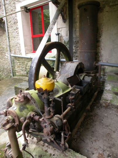 Le moteur à pistons : la préchambre de combustion (au premier plan), le cylindre (au centre), le système de graissage (en jaune), la bielle (côté latéral) et le volant toujours doté d'une courroie.