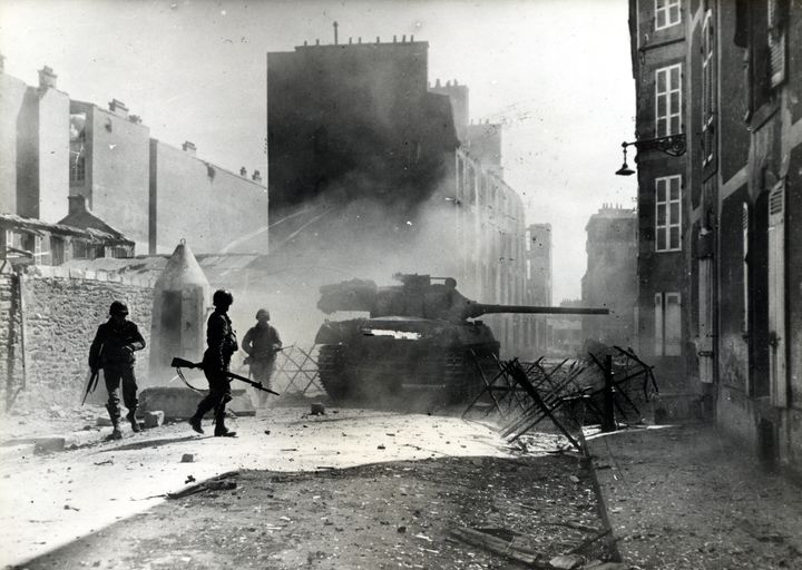 Char américain M18 Hellcat dit chasseur de char tirant rue Kerfautras. On distingue trois soldats américains armés de leur fusil à baionnette à côté d'une guérite allemande en béton armé et d'un barrage (probablement un poste de contrôle allemand)