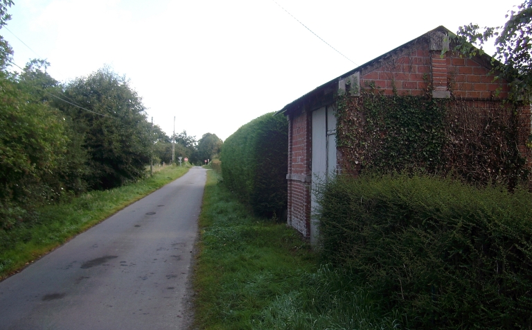 Vue générale du tracé de l'ancienne voie ferrée et du bâtiment de la halte de la Cour ; Créhen, la Cour. Ligne de chemin de fer d'intérêt local de Plancoët à Saint-Cast (premier réseau), tracé de l'ancienne voie ferrée et abri (1er quart du 20ème siècle)