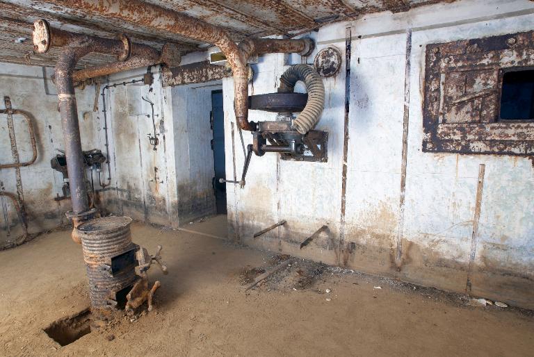 Vue de la chambre de troupe droite : poêle, système de ventilation, boitier de connexion téléphonique, créneau blindé..., photographie réalisée le 11 mai 2009