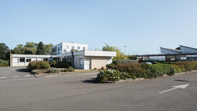 Vues d'ensemble prise du sud-ouest : bâtiment A : accueil, administration, logements ; à droite, façade ouest des ateliers. Louis Arretche et Jean Monge, architectes, plans 1959.