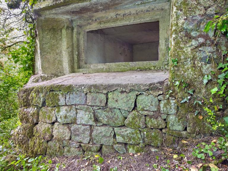 Vue du bunker - casemate de type VF pour un canon de 50 mm situé à l'extrémité Est de la pointe : embrasure rectangulaire en gradin (photographiée de l'extérieur). Le bunker est intégré dans le mur de clôture - soutènement du domaine ;  Vue de l'embrasure rectangulaire en gradin depuis l'extérieur. Le bunker est intégré dans le mur de clôture/soutènement du domaine