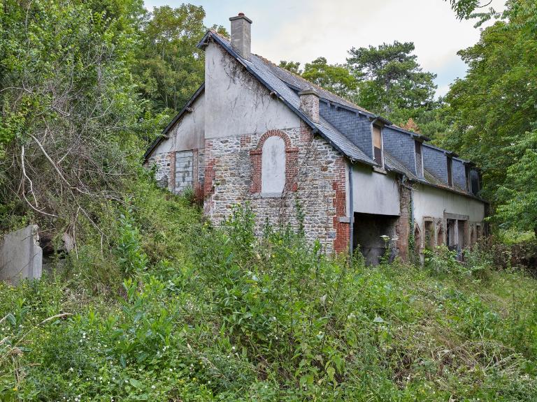Vue des communs et dépendances : pignon Ouest et élévation Sud. Le pignon est percé d'une porte haute en arc plein cintre en brique donnant accès au comble à surcroît. Deux souches de cheminée émergent du toit. En appentis, grenier arrière et porte