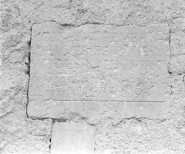 Fragment de pierre tombale réemployée dans le mur est des communs du presbytère.