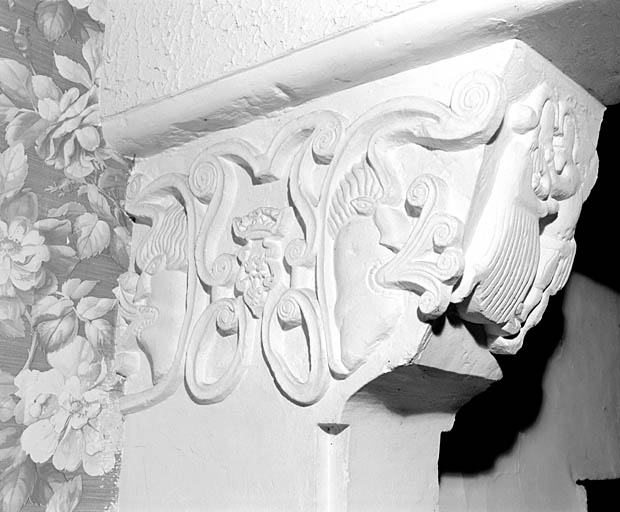 Logis, pièce nord du premier étage, cheminée, détail du corbeau de gauche, face latérale gauche : masques, rinceaux et armoiries décoratives (trois fleurs de lys).