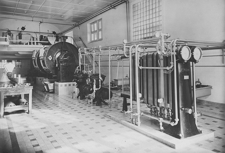 Atelier de fabrication du beurre : barattes et système de canalisation d'eau chaude et froide (photographie des années 1950).