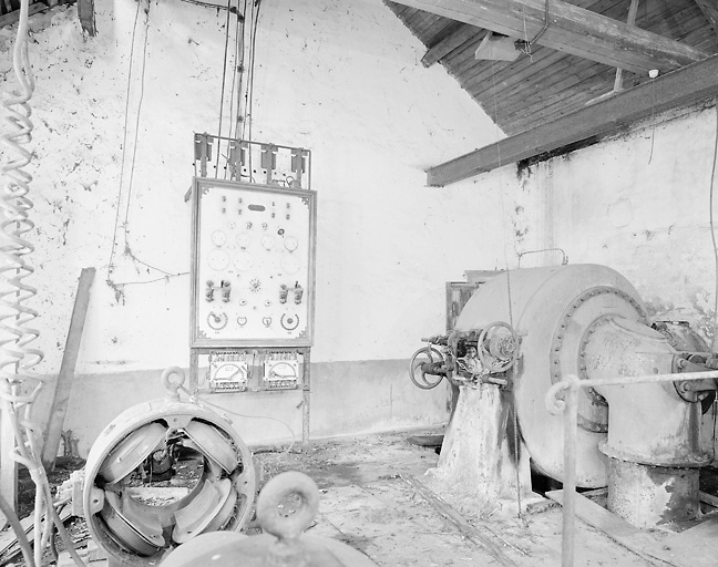 Intérieur de la centrale hydroélectrique : turbine, tableau de commande et générateur de 1904.
