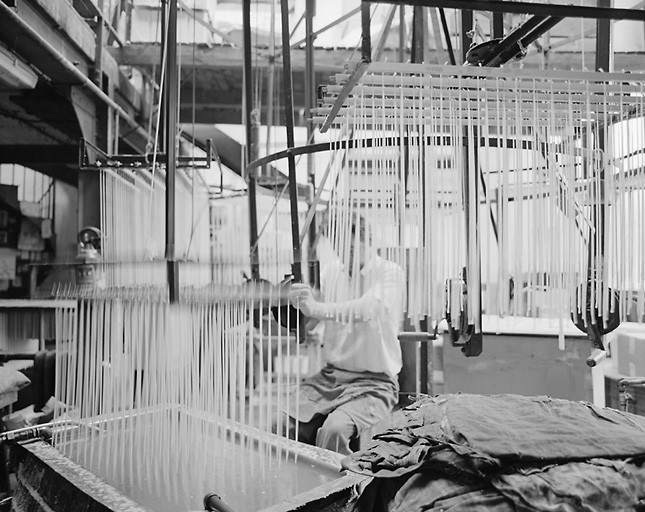 Façonnage des bougies par trempage des mèches suspendues à un plateau dans une cuve remplie de cire fondue.