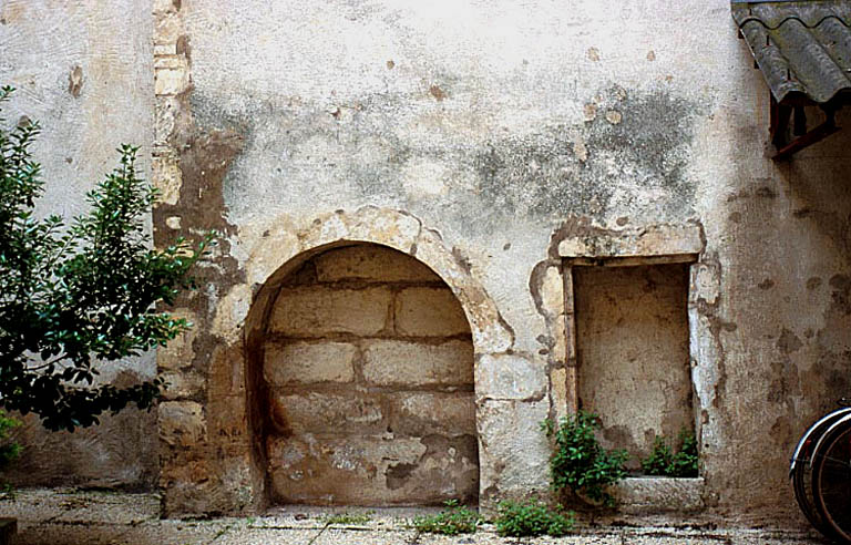 Mur latéral de la cour, ancien puits et arc.