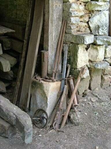 Dépendances, hangar et séchoir à tuiles, détail d'un poteau en bois sur socle de pierre.