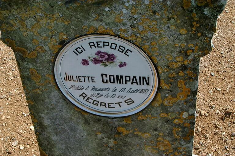 Stèle sommée d'une boule, détail de l'assiette en porcelaine décorée de violettes identifiant la personne inhumée.