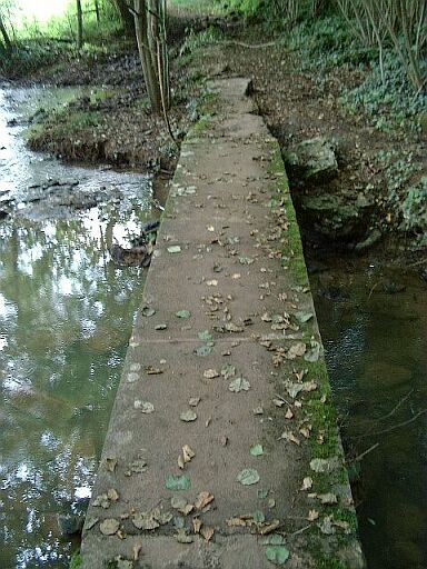 Petit pont sur le Lambon, fait de pierres posées debout couvertes de grandes dalles rectangulaires, sur le chemin rural de la Banissière à Six-Chiens, vue du tablier.