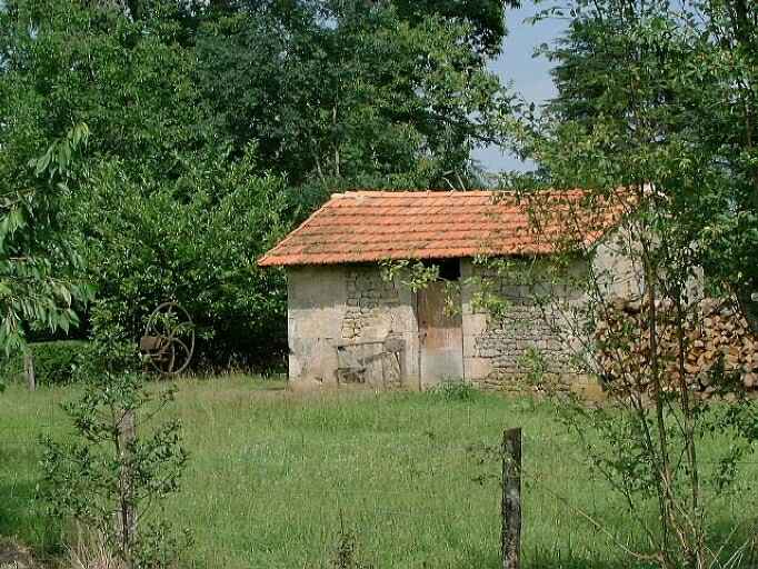 Petit bâtiment (buanderie ?) et pompe à manivelle en forme de roue.