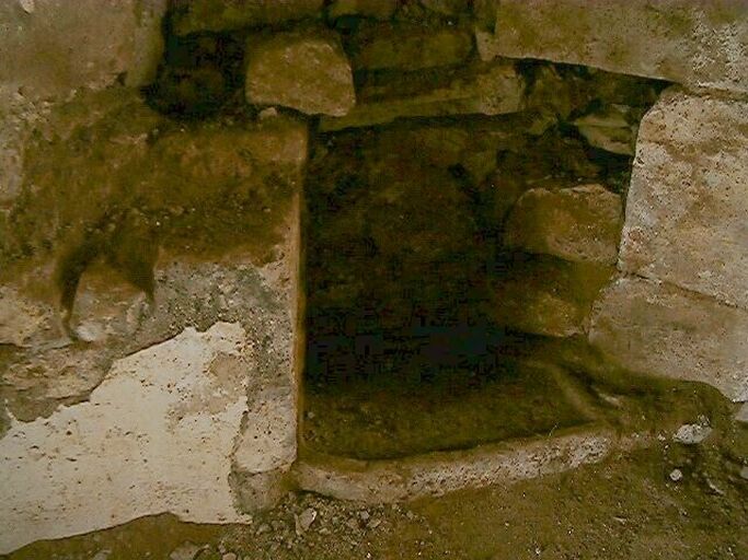 Logis principal, intérieur, rez-de-chaussée, mur nord, vestiges de la fenêtre à coussiège donnant sur l'écurie, détail du coussiège et de la pierre d'évier remployée au sol.