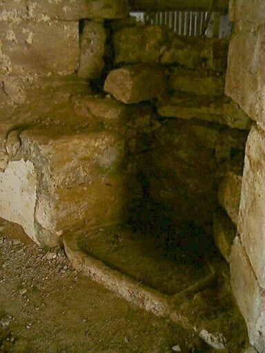 Logis principal, intérieur, rez-de-chaussée, mur nord, vestiges de la fenêtre à coussiège donnant sur l'écurie, détail de la pierre d'évier remployée au sol.