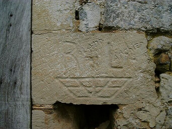 Dépendances, écurie accolée au nord du logis, élévation nord, porte, encadrement droit, pierre avec l'inscription Roland Larchier et un motif trapézoïdal gravé.