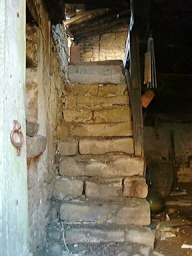 Ancien logis, intérieur, escalier en pierre en face de la porte d'entrée.