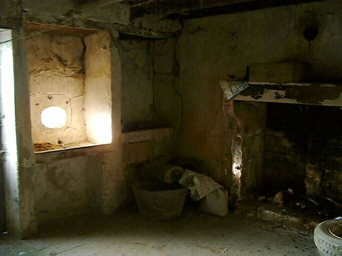 Logis, intérieur, vue de la pièce à vivre équipée d'une cheminée, potager et évier.