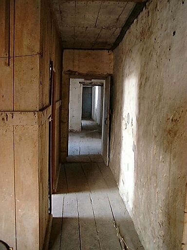 Logis, étage, couloir pratiqué du côté est par les cloisons en bois des chambres, vue depuis le grenier.