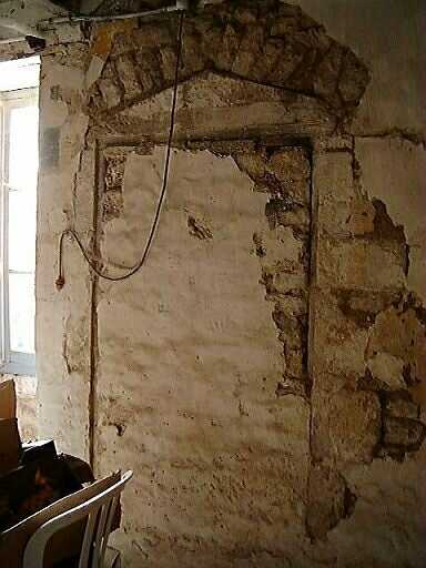 Logis, intérieur, rez-de-chaussée, pièce sud, porte murée avec linteau triangulaire et arc de décharge.